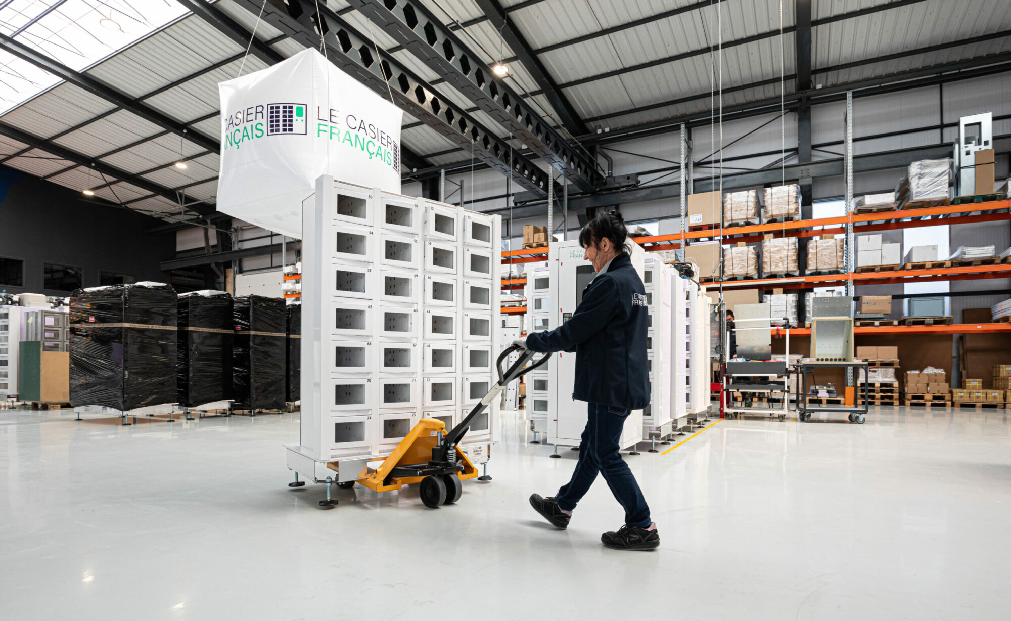 Technicienne Le Casier Français en charge de déplacer un distributeur automatique en cours de fabrication